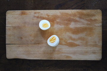 sliced boiled eggs on a wooden cutting board, top view