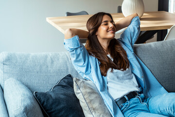 Portrait of a girl relaxing on a sofa after work at home sitting on a sofa in the living room at...
