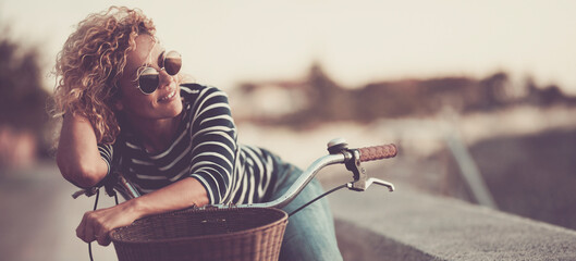 One cute woman smile and enjoy outdoor leisure activity alone having relax on her bike. Happy female people smile and look wearing sunglasses. Healthy transport lifestyle people sustainability - obrazy, fototapety, plakaty