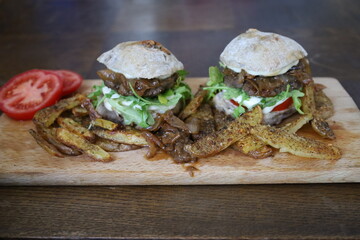 two delicious homemade rustic burgers with fries on wooden table