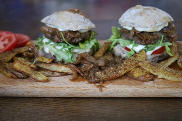 two delicious homemade rustic burgers with fries on wooden table