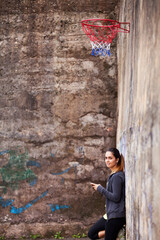 young woman leaning against a graffiti-covered wall in an urban setting - 750972501