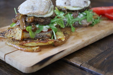 closeup homemade rustic mini burgers and baked potatoes on wooden board