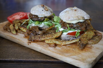 home made rustic mini burgers and baked potatoes on wooden board