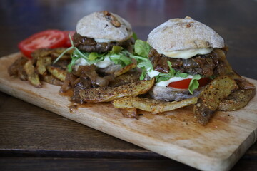 home made rustic mini burgers and baked potatoes on wooden board