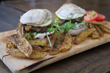 closeup homemade rustic mini burgers and baked potatoes on wooden board