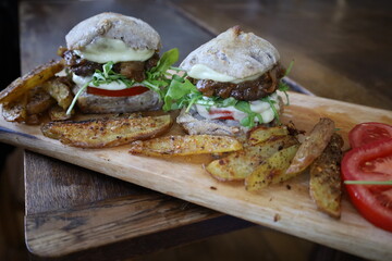 home made rustic mini burgers and baked potatoes on wooden board