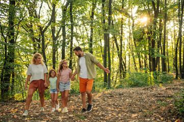Naklejka na ściany i meble A happy family is walking in nature and having adventure in forest.