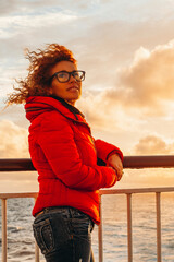 Young adult tourist woman enjoy warm orange sunset on the dock of a ferry boat ship during holiday...