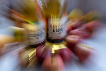 A zoom burst background of bottles of vintage cider surrounded by apples.