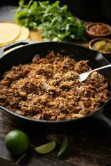 carnitas in skillet pan with tacos ingredients