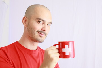 casual bald man holding a switzerland flag printed mug ,swiss coffee and chocolate beverage advertising template 