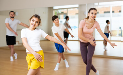 Fototapeta na wymiar Happy sporty family of four enjoying active dance in modern studio. Focus on smiling brunette teenage girl..