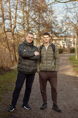 Father-Son Bond: Handsome 40-Year-Old Man and 17-Year-Old Son Standing Together in Winter or Autumn Park.