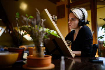 Portrait of talented artist with headphones creating artwork at home.