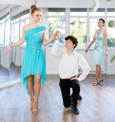 Young couple of teenagers in evening dresses are learning to dance an polonaise dance