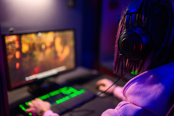 Rear view of a esport gamer wearing headphones and playing online video game
