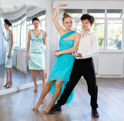 Dance teacher teaches a girl and boy couples ballroom dancing