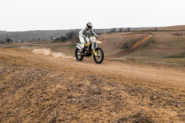 Person riding a motocross motorcycle on a dirt road with helmet on