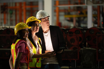 professional engineer,worker,technician use clipboard discuss work, walk in steel metal manufacture factory plant industry. Black African American man and woman wear hard hat check quality machine