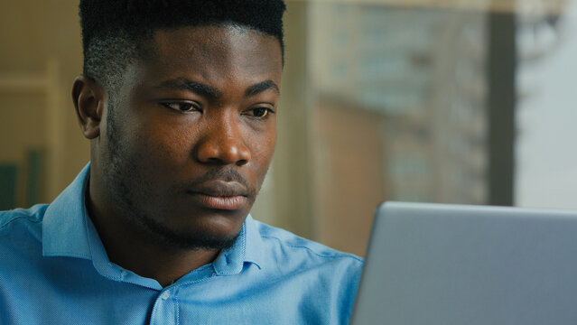African American business man employee professional manager working on laptop computer from home office male ethnic executive studying browsing web focused businessman analyzing digital data online