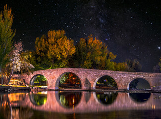 puente antiguo sobre rio en noche estrellada - obrazy, fototapety, plakaty