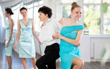 Girl and boy in evening dresses learn to dance the foxtrot in a choreographic studio