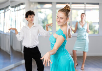 Girl and boy in evening dresses learn to dance the foxtrot in a choreographic studio