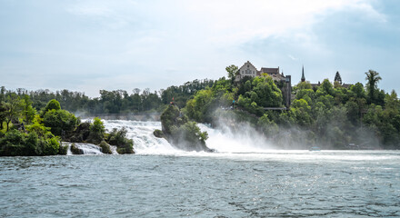 Tourists watch the impressive waterfalls below Laufen Castle at the Rhine Falls from the rocks and...