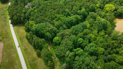 Car driving on country road past green fields and trees on vacation while camping outdoors at Staunton River State Park in Virginia