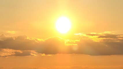 Golden sunset with clouds and orange sky in heavens shining in warm summertime weather in nature outdoors