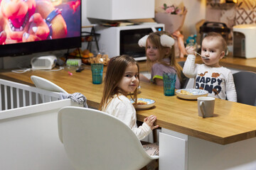 Group of Children Sitting at a Kitchen Table Eating Food