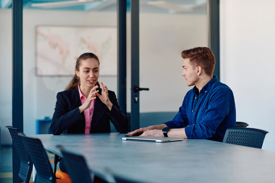 A business leader in a suit conversing with her worker in the IT industry about new business projects and existing business problems