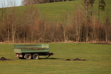 A green trailer is parked in a field - 750998504