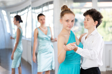 Motivated adolescent ballroom dancers, girl and boy in performance outfit practicing elegant dance...
