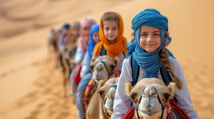  smiling children riding their camels traveling in the UAE desert in a sunny morning © Salsabila Ariadina