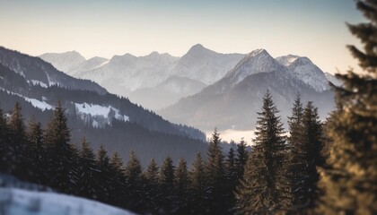 mountain landscape with spruce and pine trees in the austrian alps during a bright sunny day in winter time distant mountains and mountain chains fade out with lighter color tones