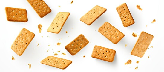 A group of rectangular crackers is scattered across a white surface, creating a burst of crunchy snacks in motion.