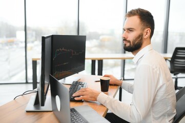 Crypto trader sits at his workplace in front of a monitor with charts.