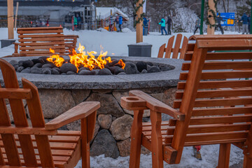 chairs around a NH ski area firepit skiers and chair lift in background