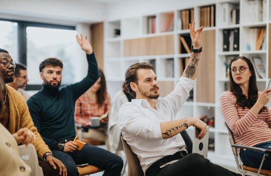 Engaged participants raising hands in a diverse workshop or seminar. - Powered by Adobe