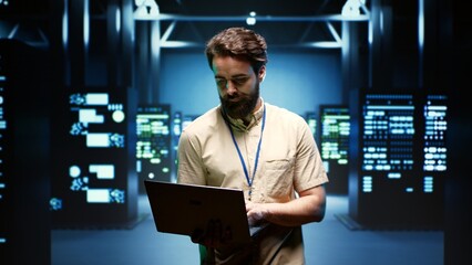 System administrator walking between operational server racks in computer network security data...