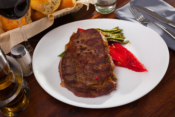 Appetizing roasted beef steak with braised green beans and bell pepper on white plate