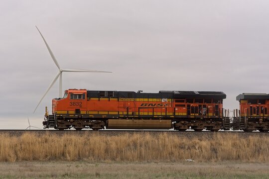 Burlington Northern Santa Fe train passes wind farm in plains of Kansas on May 15, 2023