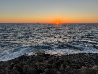 Sunset on the Mediterranean Sea with a far away seen island in the distance at Malta 