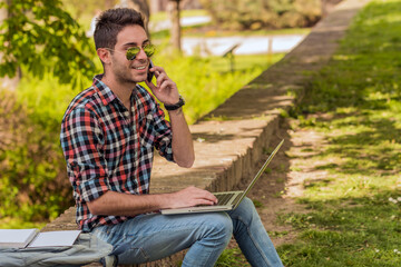 College student with book. Student guy doing homework in the park.