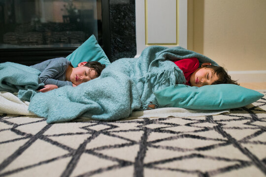 two young brothers asleep in front of a fireplace
