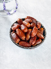 Dates Fruit in Bowl and Water Glass with Prayer Beads on Gray Concrete, Ramadan Suhoor Concept, Copy Space