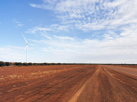 Outback road and red dirt with wind turbine, in Western Australia