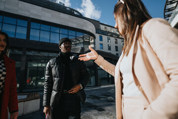 Obraz premium A professional man and woman engage in a friendly discussion outside an office building. Captures a sense of partnership and cooperation.